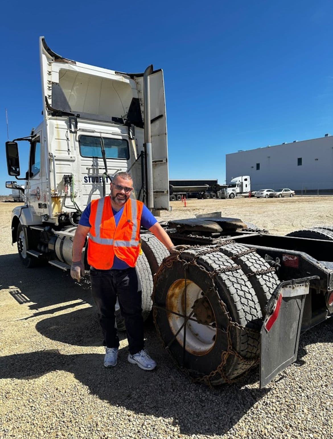 Student in safety gear standing beside a True North training truck marked STUDENT